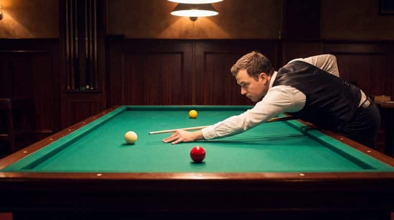 Joueur de billard carambole en position de tir sur la table
