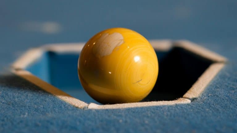 Bille jaune arrêtée dans l’entrée de poche d’une table de pool